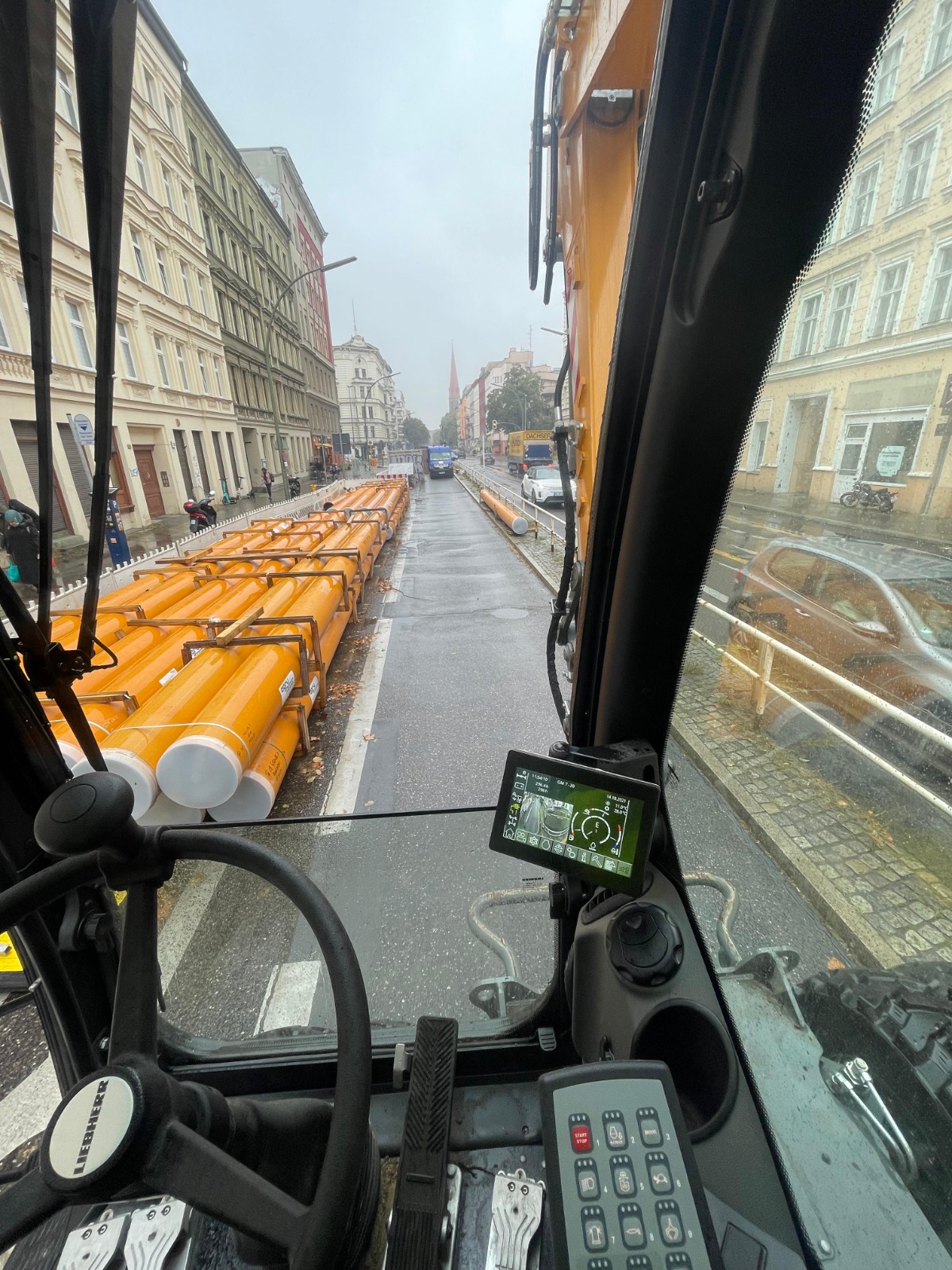 Blick aus der Baggerkabine auf die Baustelle mit gelben Rohrleitungen