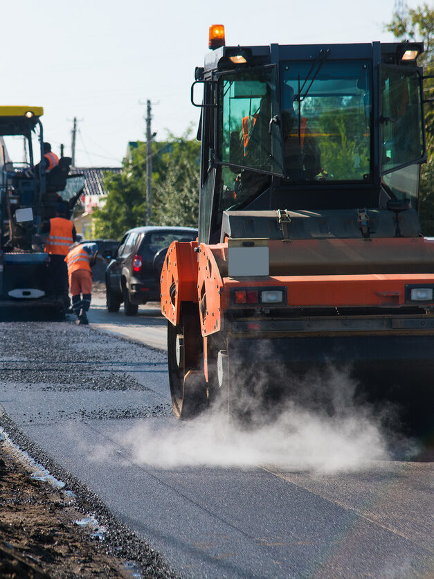 Repair of the old and construction of a new asphalt road. The excavators, graders and road rollers working on the new road construction site.